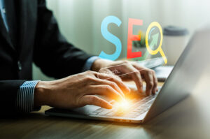 Professional working on SEO optimization with a laptop, utilizing a search engine interface and digital tools for boosting website traffic and improving online visibility in a modern workspace.